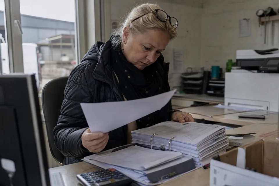 Właścicielka hurtowni czyta pismo od komornika i porównuje je z segregatorem niezapłaconych faktur