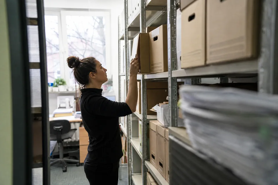 Pracownica firmy kupującej wierzytelności wyjmuje teczkę sprawy z archiwum